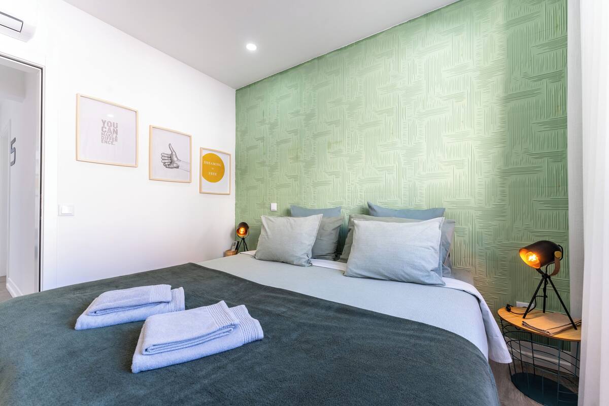 A neatly made bed with folded towels, a bedside lamp, and framed motivational posters on the wall.