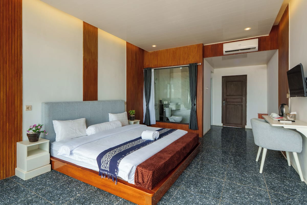 A modern hotel room with a large bed, a desk, and a television.