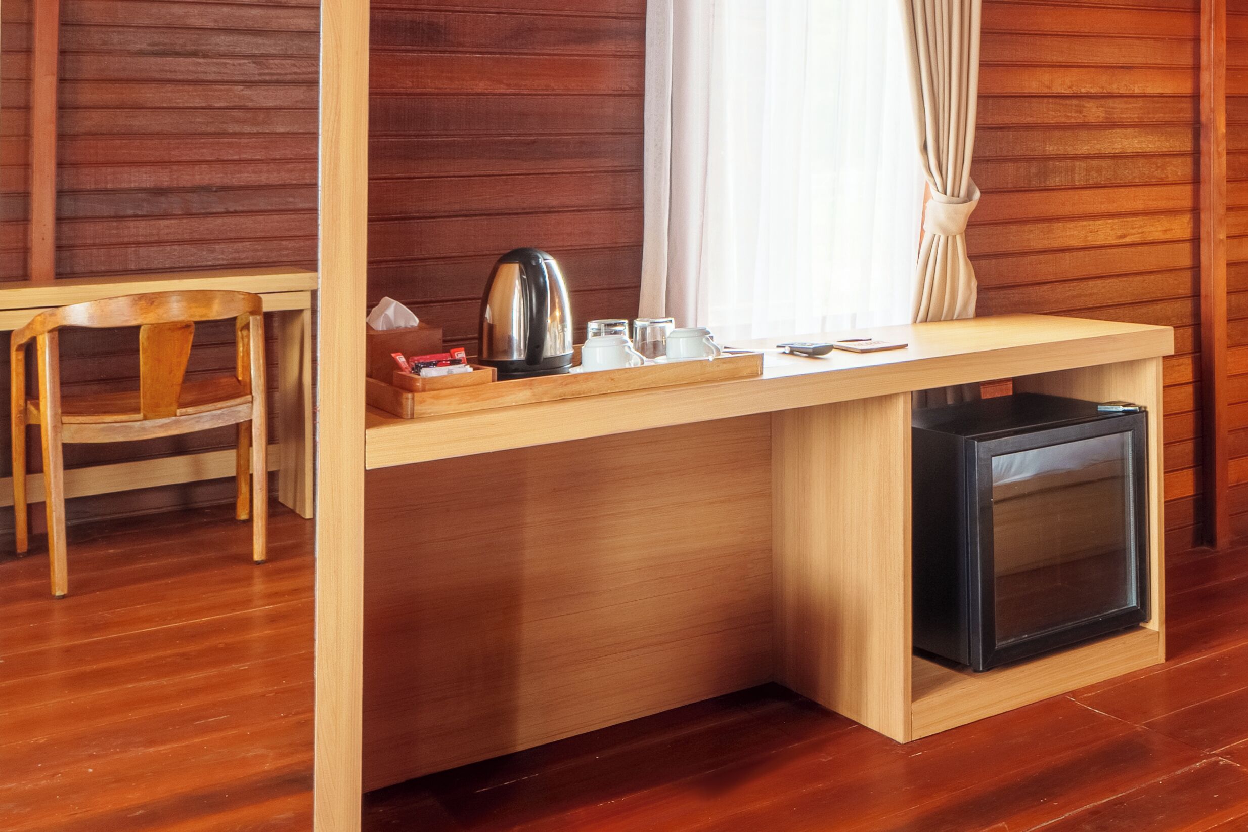 Un escritorio de madera con un televisor, una tetera y una taza.