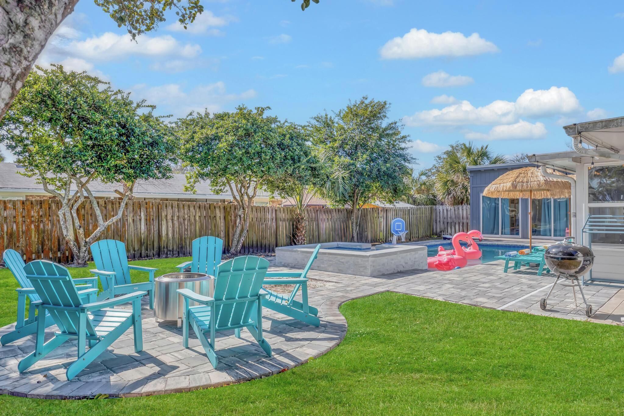 A backyard with a patio area, outdoor seating, a barbecue grill, and a swimming pool.