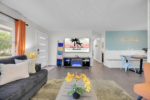 A modern living room with a sofa, coffee table, and a TV displaying 'Place To Be Rentals'. - Seaside Paradise: Dive into Luxury with Saltwater Pool, Spa, and Chemical-Free Bliss (Ponte Vedra Beach)