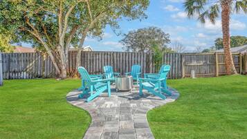 A patio area with a stone pathway, turquoise chairs, and a metal table.