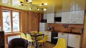 A modern kitchen with white cabinets, a black stove, and a yellow dining area with a table and chairs.