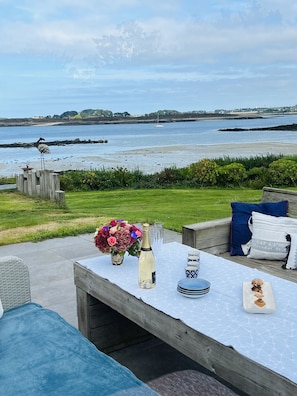 An outdoor seating area with a table set for two, overlooking a body of water and a distant shoreline. - very quiet Mansion with 280° seaview + privat access to the sea + big garden (Landéda)