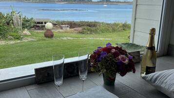 Een balkon met uitzicht op zee, een fles champagne en een bloevas.