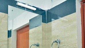 A bathroom with a white sink, a mirror, and a towel ring. - Sree Karpagam Dreams (Port Blair)