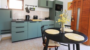 Une cuisine avec des armoires de couleur turquoise, une table noire et un vase rempli de fleurs jaunes.