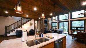 A spacious kitchen with a large island, a built-in stove, and a stone fireplace.