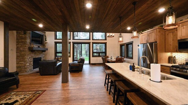 A spacious kitchen with a large island, wooden cabinets, and a stone fireplace.
