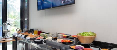 A buffet with various food items and a television displaying a scenic landscape.