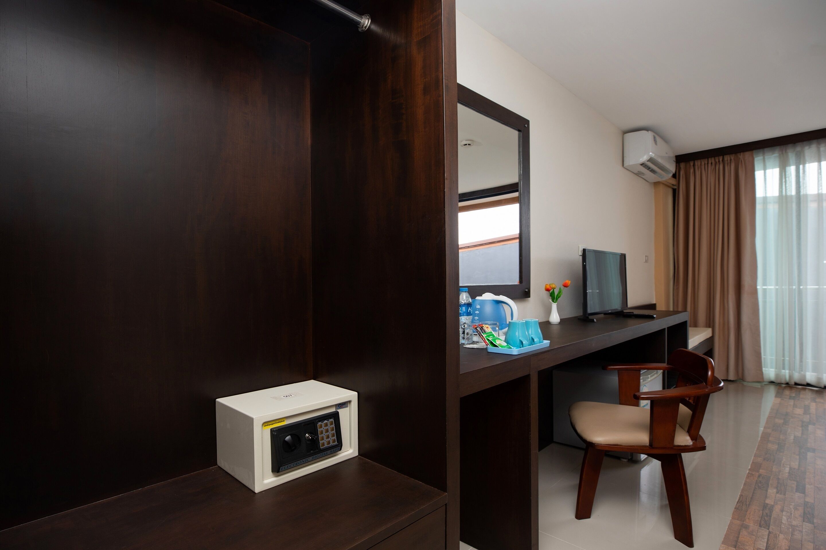 Une chambre d’hôtel avec une armoire en bois foncé, un bureau avec une chaise, une télévision et un four à micro-ondes.