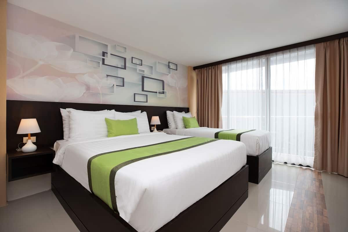 A hotel room with two beds, a modern wall design, a large window with curtains, and a clean, polished floor.