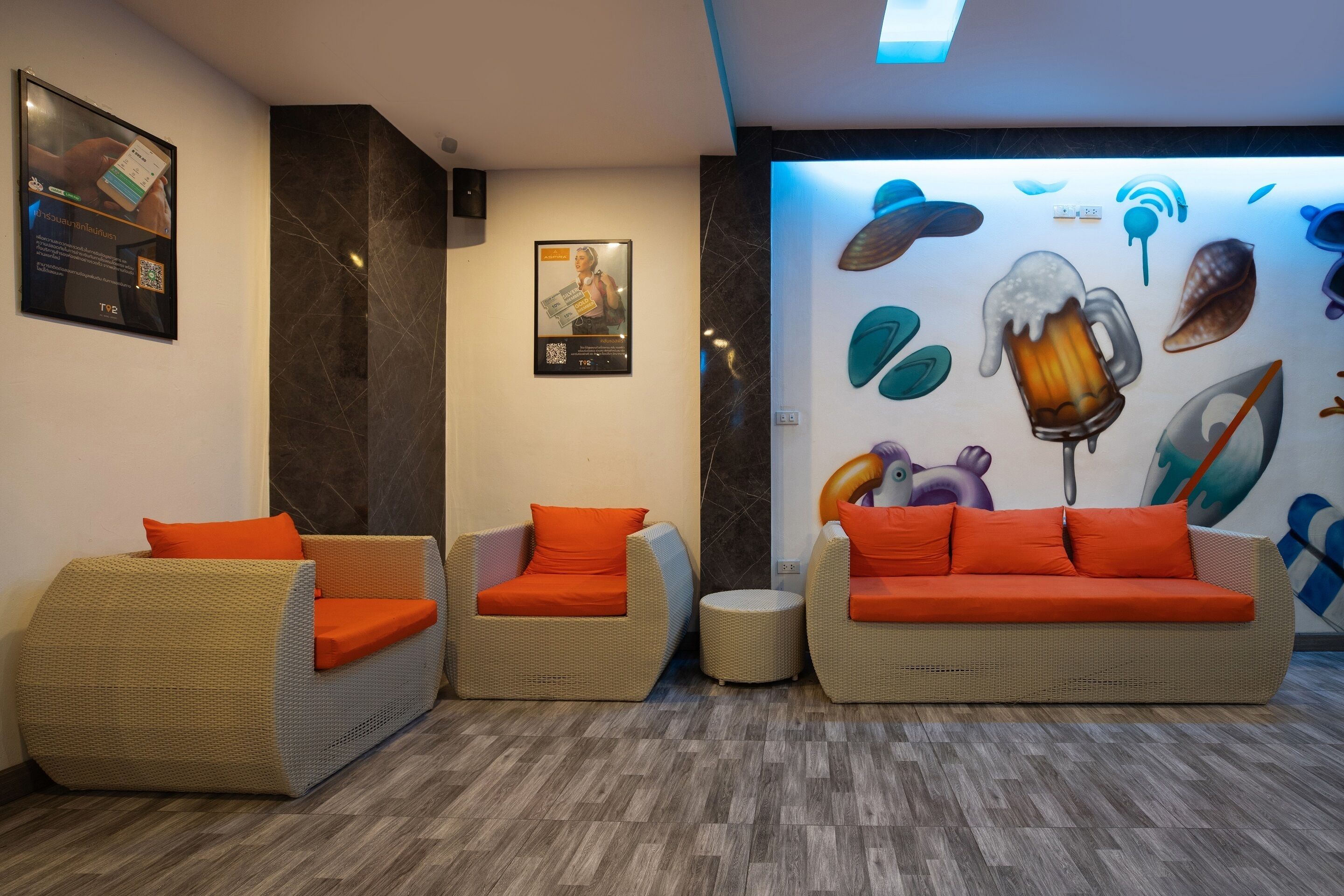 A lobby with wicker sofas and chairs, a wall with a mural, and a QR code on the wall.