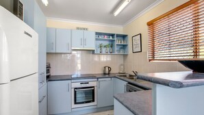 Uma cozinha moderna com armários azul-claros, forno embutido e bancada com chaleira.