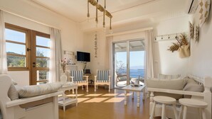 A bright living room with a sofa, chairs, a coffee table, and a TV.