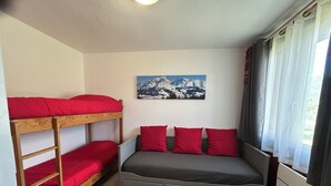 Una camera in stile dormitorio con letti a castello e un divano letto.