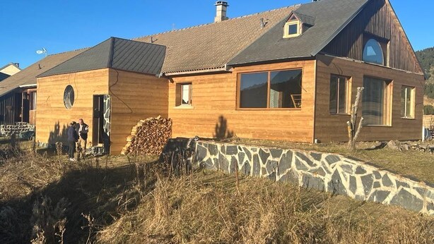 Una casa in legno con fondamenta in pietra, ampie finestre e un tetto spiovente.