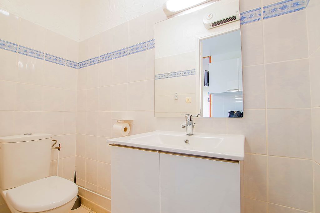 Een badkamer met toilet, wastafel en spiegel.