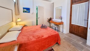 A bedroom with a bed, bedside lamp, dresser, mirror, and a door. - Skarinou Village Poolside Escape Studio (Skarinou)