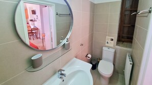 A bathroom with a sink, toilet, and mirror. - Skarinou Village Poolside Escape Studio (Skarinou)