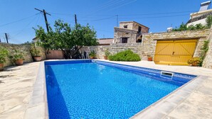 A rectangular swimming pool with a tiled edge, surrounded by stone walls and potted plants. - Skarinou Village Poolside Escape Studio (Skarinou)