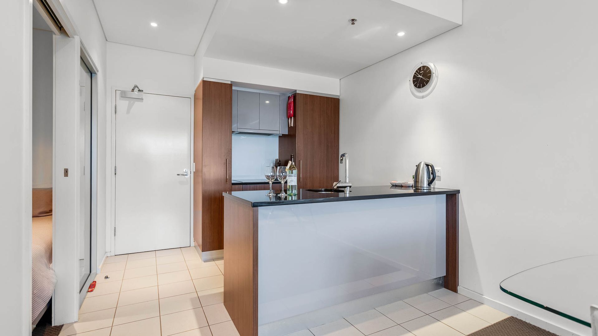 A modern kitchen with a central island, a built-in oven, and a stainless steel sink.