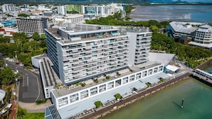 Un hotel moderno de varios pisos con una terraza en la azotea, situado cerca de la costa.