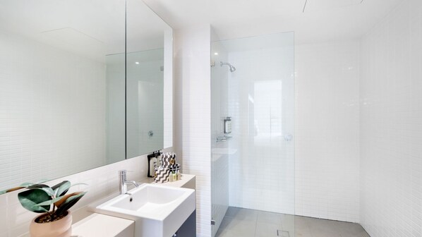 Un baño moderno con un espejo grande, un lavabo y una zona de ducha.