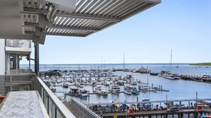 Un puerto deportivo con numerosas embarcaciones amarradas, cielo despejado y vista al mar.