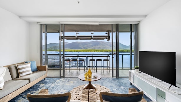 Una sala de estar moderna con un balcón que da a un lago y montañas.