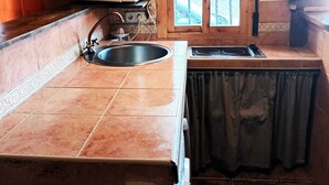 Uma cozinha compacta com pia, micro-ondas e janela com grades decorativas de ferro.
