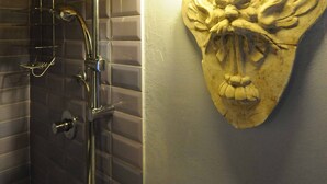 Un baño con ducha, una lámpara de pared y un relieve decorativo de piedra.