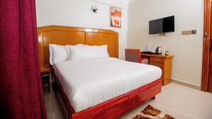 Habitación de hotel con una cama de madera, un televisor montado en la pared, un escritorio con silla y una cortina roja.