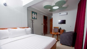 Habitación de hotel con una cama grande, una mesita, una silla, televisión y ventilador de techo.