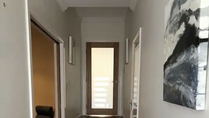 Un corridoio con pavimento in legno, una scala e una porta che dà su un'altra stanza.