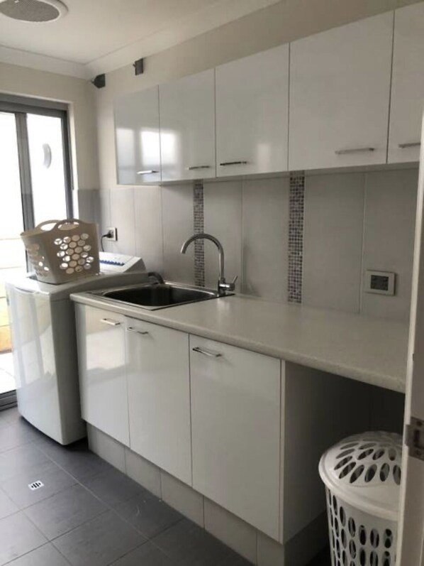 A modern kitchen with white cabinets, a stainless steel sink, and a tiled backsplash.