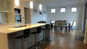 Una cucina moderna con angolo bar, pavimento in legno e zona pranzo con sedie e tavolo.