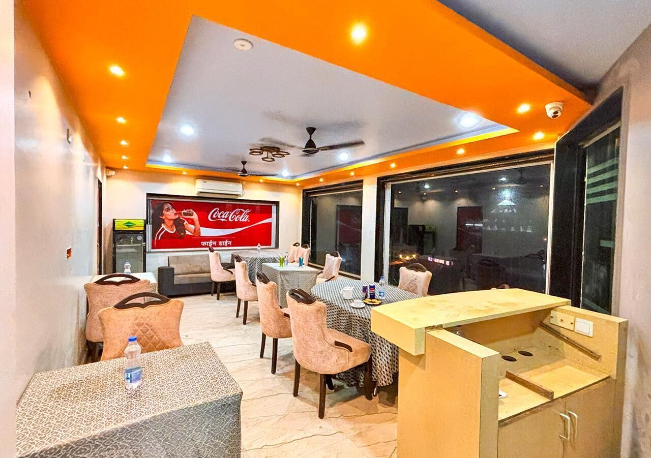 Un comedor con mesas y sillas, un anuncio de Coca-Cola y un ventanal grande.