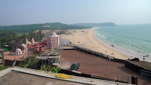 A beach with a temple complex in the background. - SUKHSAGAR BEACH RESORT Kunkeshwar  (Devgad)