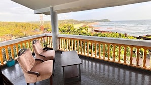 A balcony with seating, a view of the ocean, and a railing. - SUKHSAGAR BEACH RESORT Kunkeshwar  (Devgad)