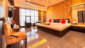 A modern hotel room with a large bed, a seating area, a television, and a view of the ocean. - SUKHSAGAR BEACH RESORT Kunkeshwar  (Devgad)