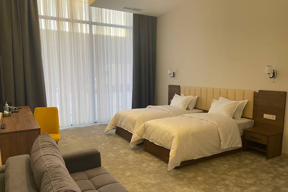Una habitación de hotel con dos camas, un sofá, un escritorio y una silla.
