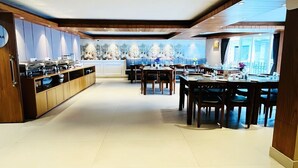 A spacious hotel lobby with a central seating area, a buffet counter on the left, and a large window providing natural light. - The Retreat (Darjeeling)