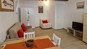 Una sala de estar acogedora con un sofá, una silla, una mesa de madera y un televisor.