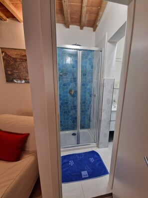 Ein Badezimmer mit einer Duschkabine, einem weißen Waschbecken und einer blauen Fliesenwand.