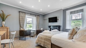 Een slaapkamer met een bed, een televisie, een open haard, een bureau en een stoel.