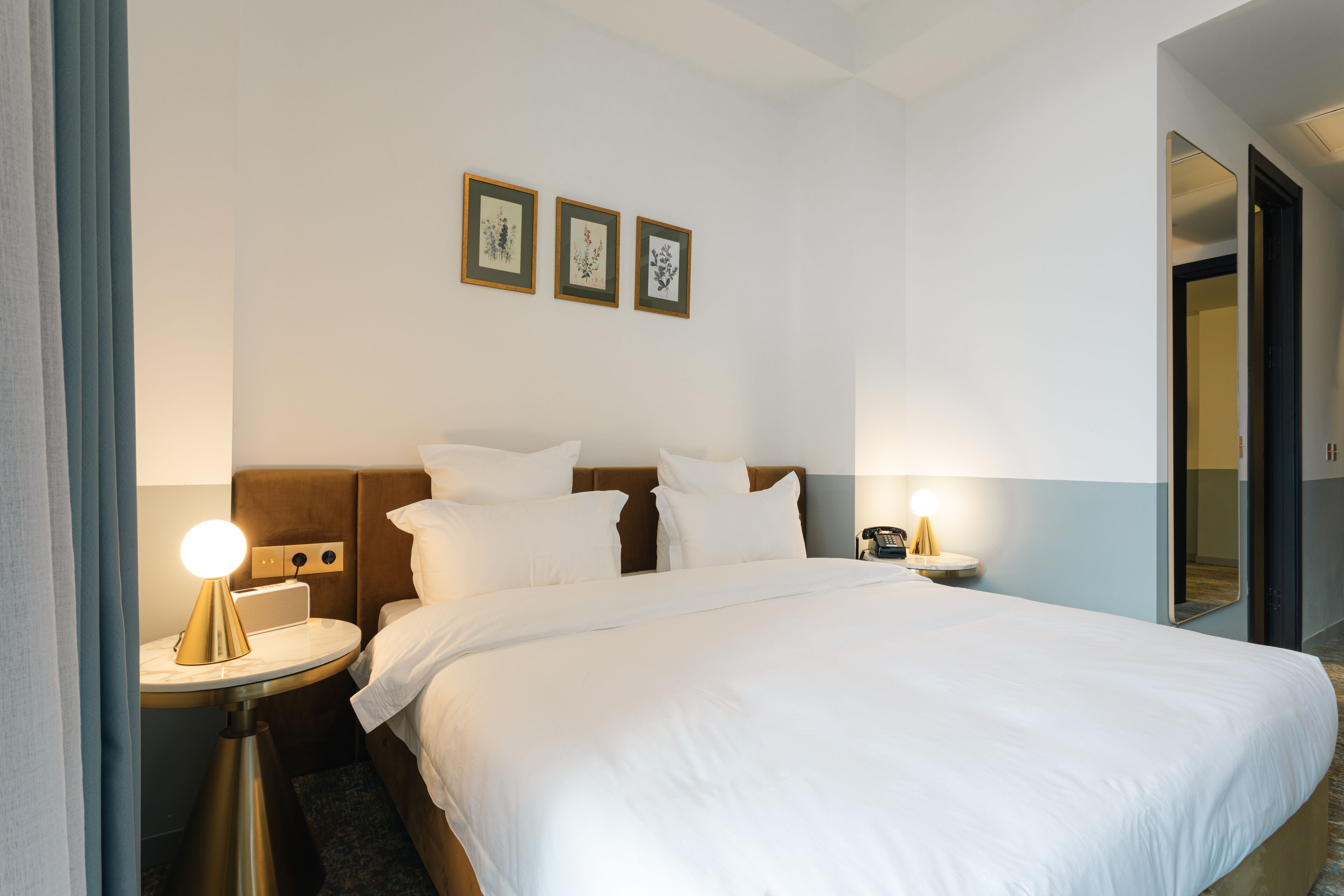 A hotel room with a large bed, two bedside tables, a nightstand, and a mirror.