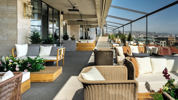 A rooftop terrace with wicker furniture, a sofa, and potted plants. - Castor & Pollux Hotel (Tbilisi)