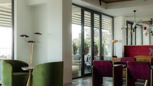 A modern interior with green and red upholstered chairs, a floor lamp, and a red accent wall. - Castor & Pollux Hotel (Tbilisi)