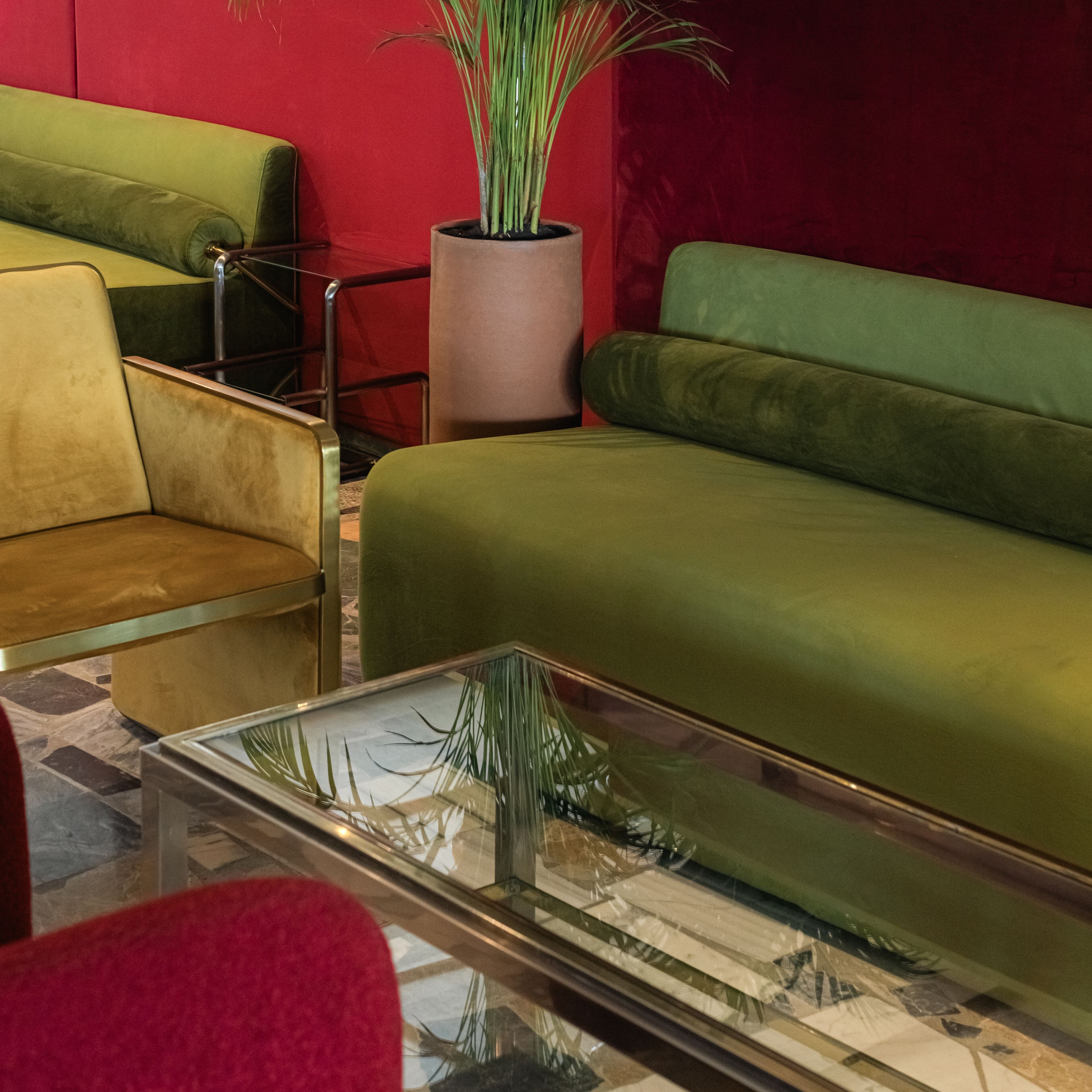 Una sala de estar moderna con un sofá verde, un sillón amarillo y una mesa de centro de vidrio.